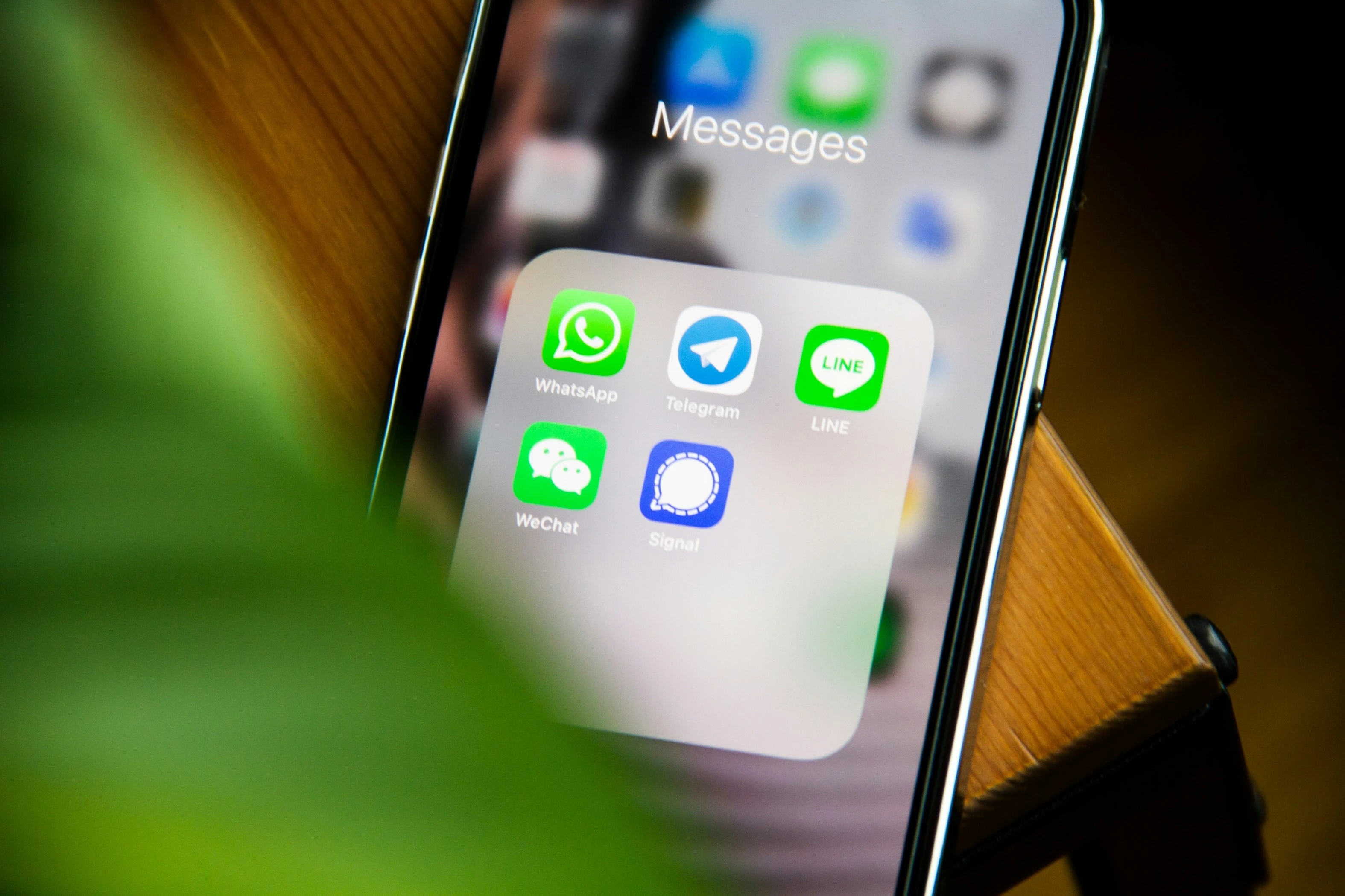 A person holding mobile phone with message widget open, with WhatsApp, Telegram, Line, WeChat Signal apps visible.